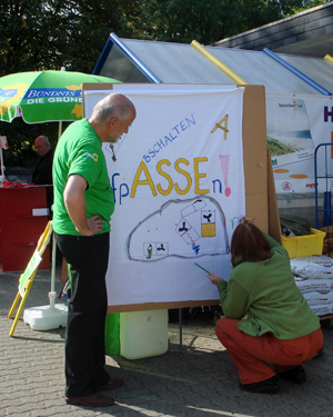 Besucher malen am Infostand der Gr&uuml;nen ein Transparent